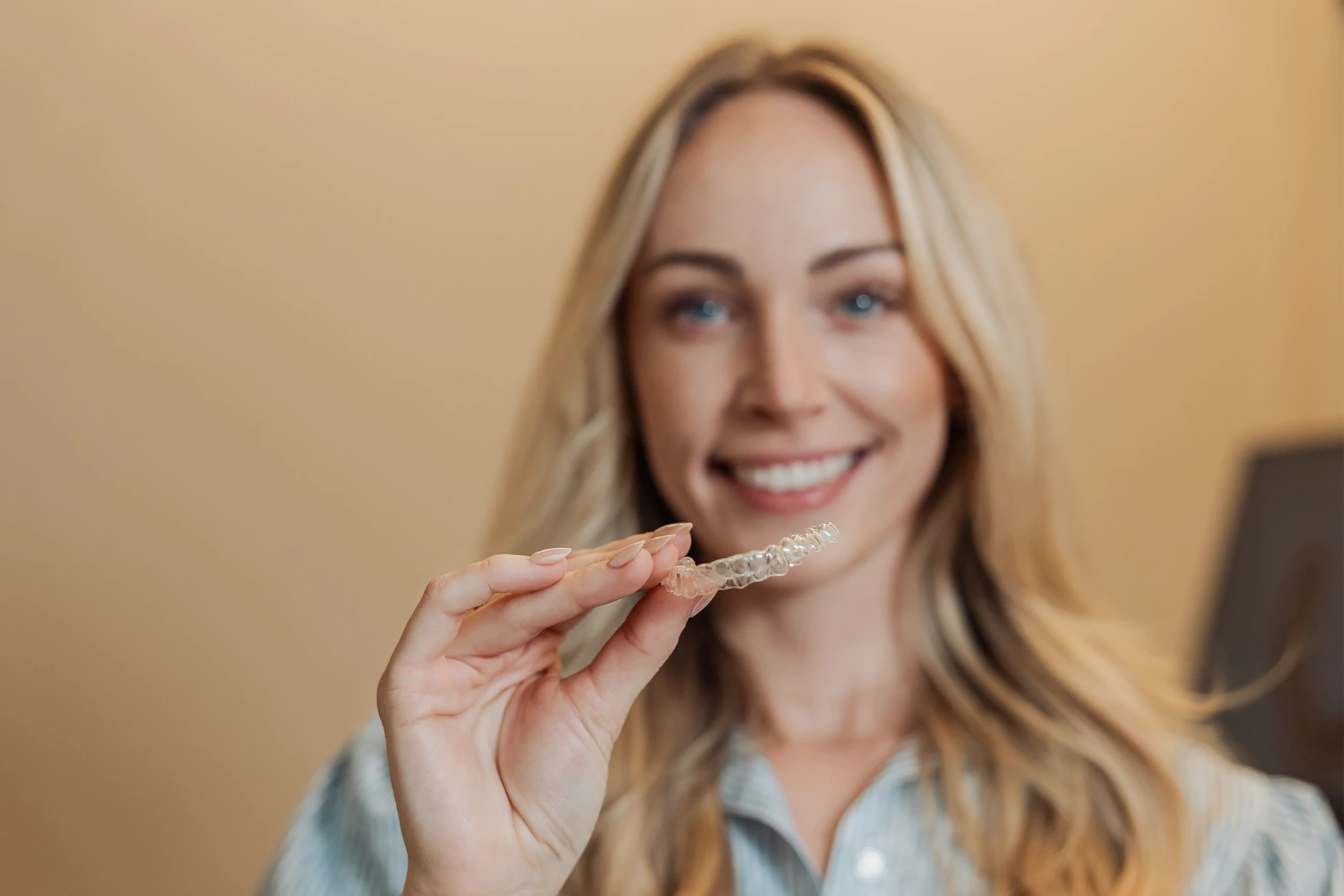 Patientin in der Praxis in Schwabing hält eine transparente Alignerschiene in die Kamera