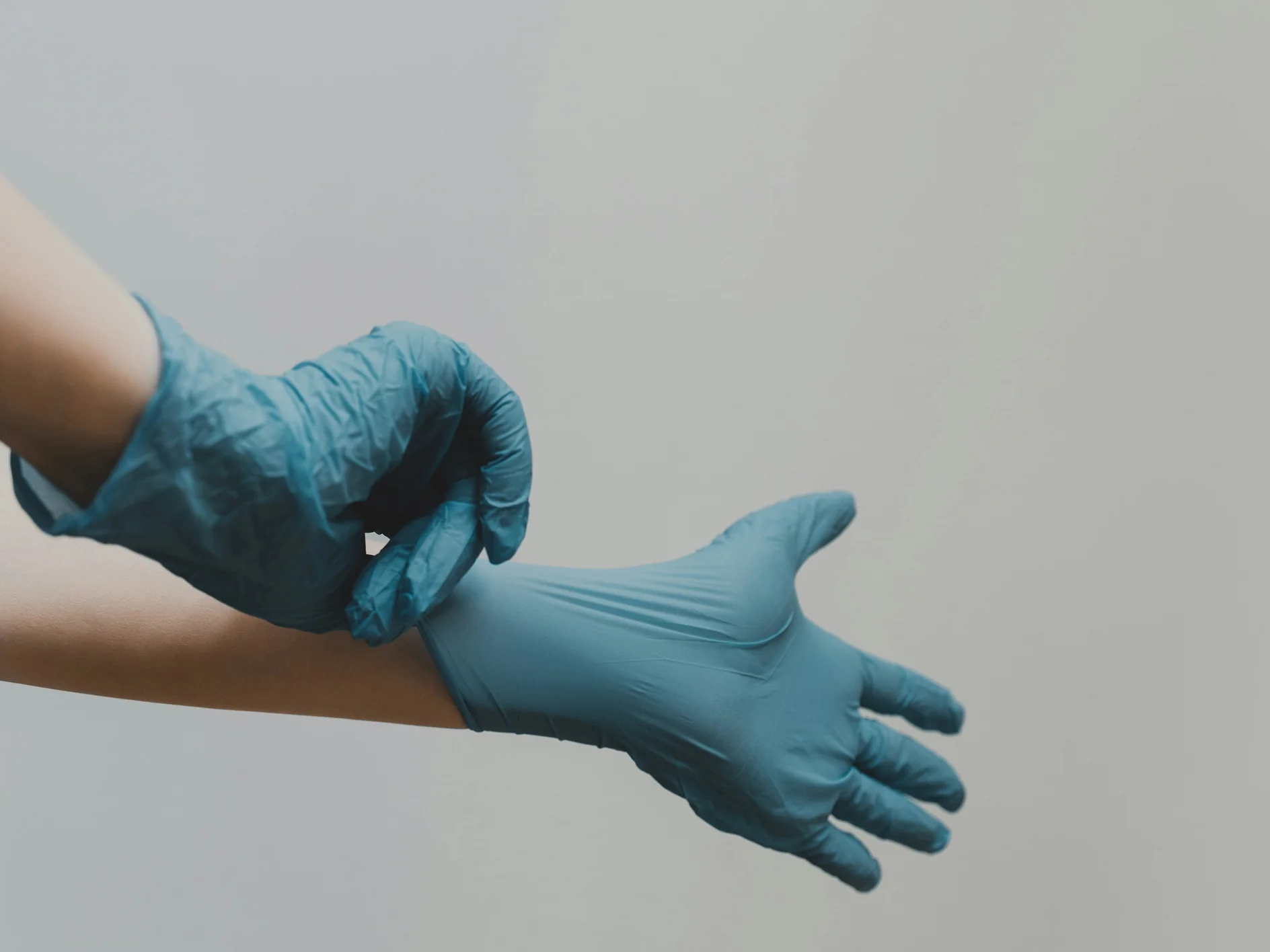 Hände ziehen blaue Einweghandschuhe an, Themenbild zur Knirscherschiene beim Kieferorthopäden in München