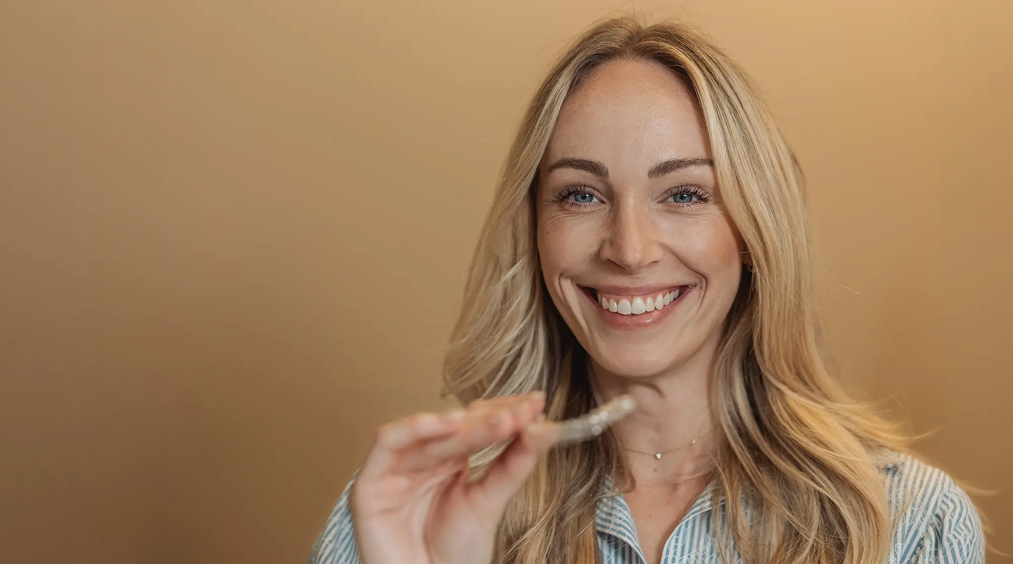 A patient at an orthodontist's office in Munich is holding a clear aligner in her hand