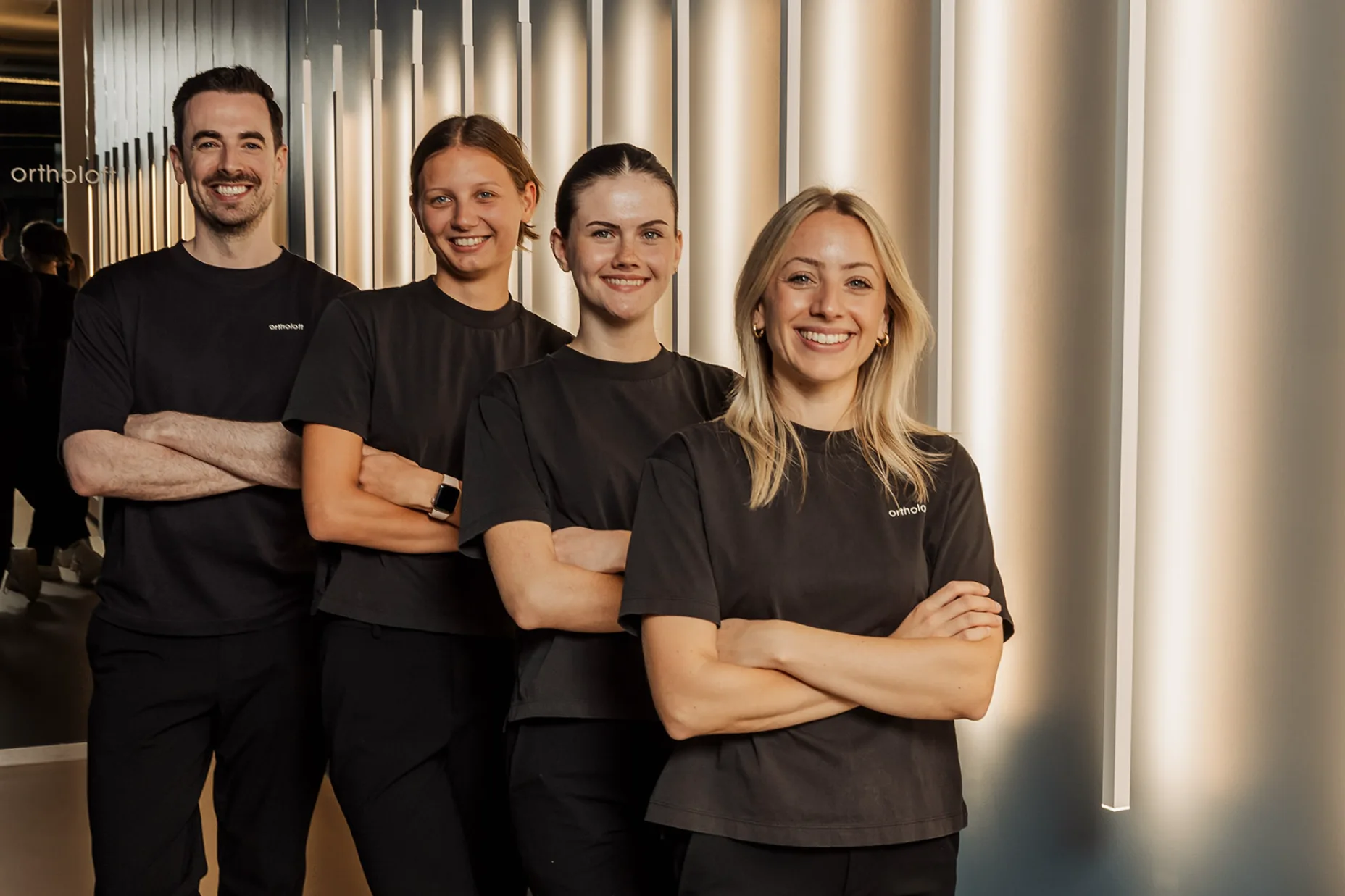Dr. med. dent. Dominik Pfeil mit dem Praxisteam von ortholoft im Flur der Praxis in der Nordendstraße im Münchner Norden