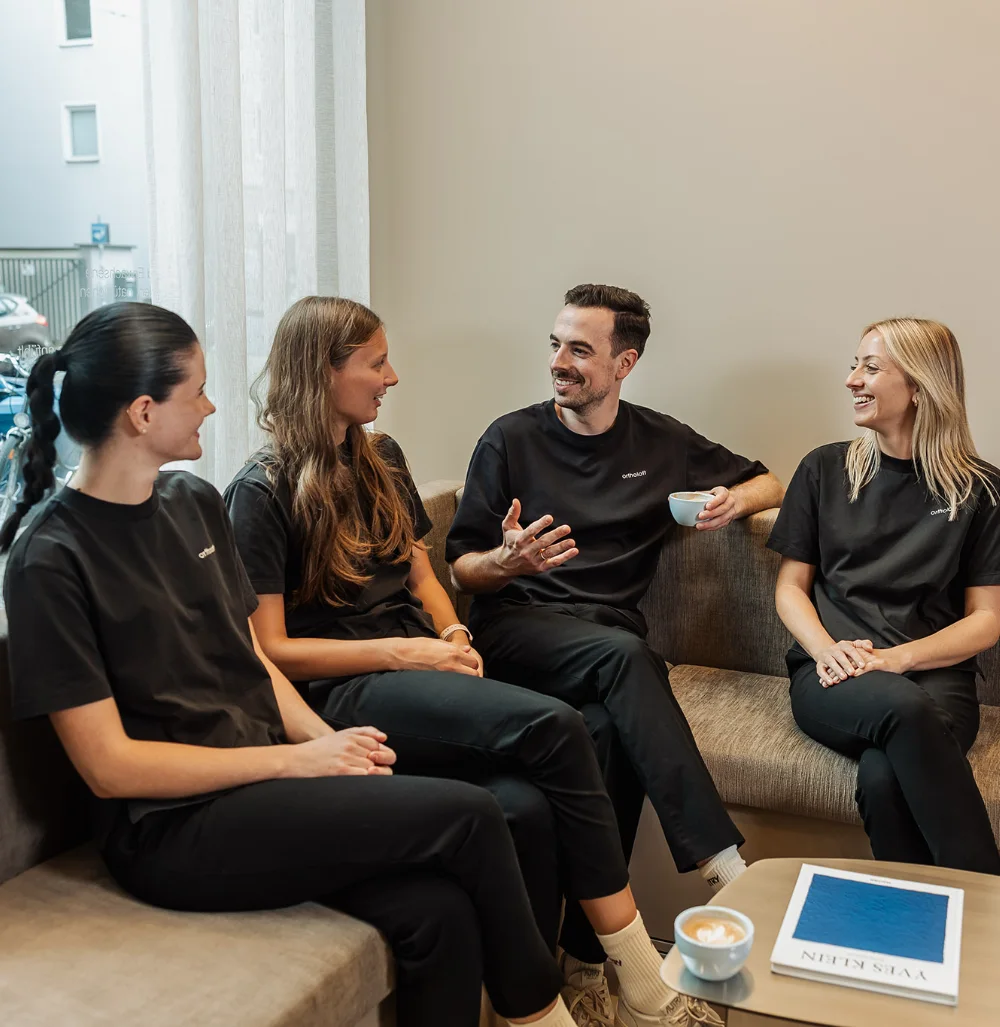 Das Team von ortholoft im Wartebereich der Praxis in München, im Gespräch bei einer Tasse Kaffee