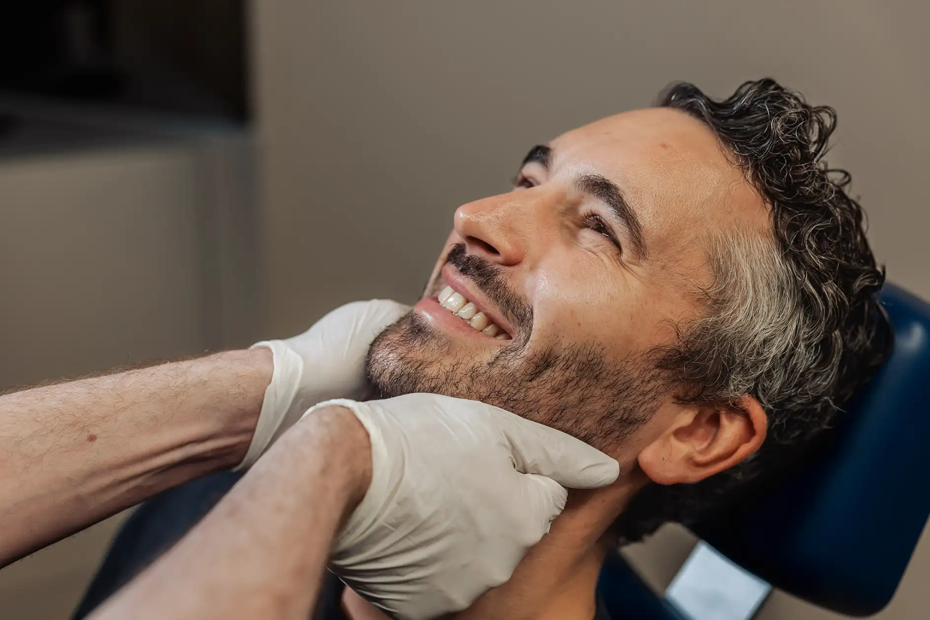 Behandler tastet bei einem liegenden Patienten den Unterkiefer ab in München-Schwabing